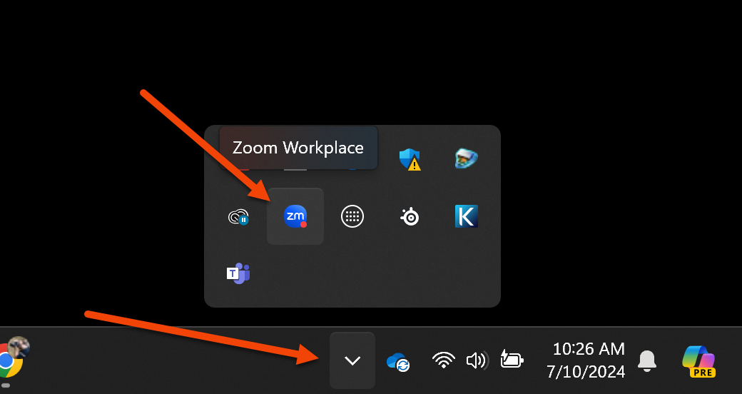 The image shows the bottom-right corner of a Windows desktop screen, specifically the system tray area. There are two red arrows highlighting different parts of the image:  The first arrow points to an icon within the expanded system tray, labeled "Zoom Workplace." This indicates that the Zoom Workplace application is running and has a notification. The second arrow points to the button used to expand or collapse the system tray icons. This button, when clicked, shows or hides additional icons from the system tray.